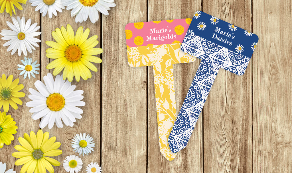 Two finished Unisub sublimation garden stakes with colorful designs, one says Marie's Marigolds and the other says Marie's Daisies.