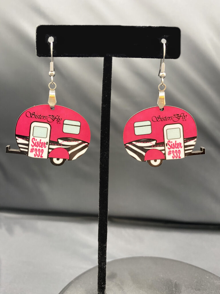 Sublimated earrings with #332 and Sisters on the Fly printed on them, which is the name of Janice's group.